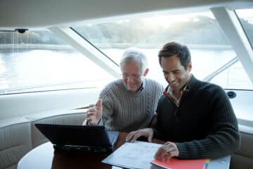 Un fils qui aide son père qui vérifie les documents obligatoires sur son bateau